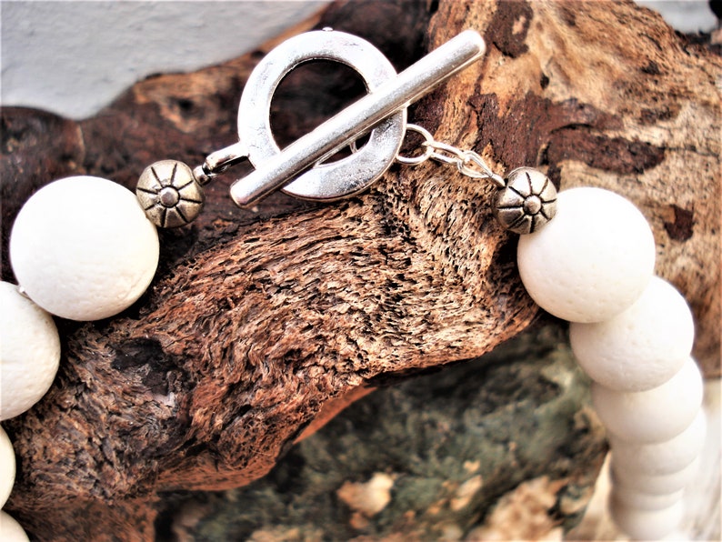 May include: White bead necklace with a silver toggle clasp. The beads are round and have a slightly textured surface.