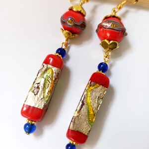 May include: Red and gold dangle earrings with a round and rectangular glass bead design. The beads have a silver and gold foil pattern.