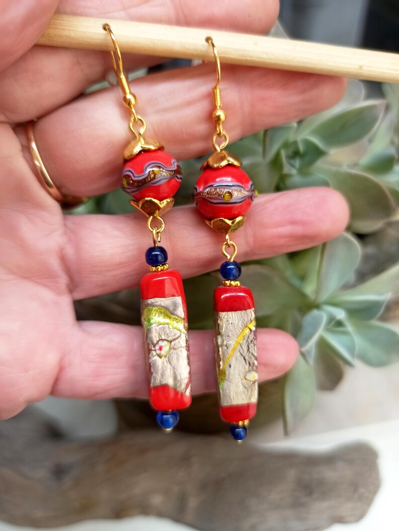 May include: Gold dangle earrings with red and gold patterned glass beads and blue glass beads.