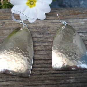 May include: A pair of silver earrings with a hammered texture. The earrings are shaped like a teardrop and have a hook fastening.