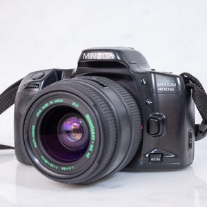 May include: A black Minolta Maxxum 400si film camera with a black lens and a black strap.