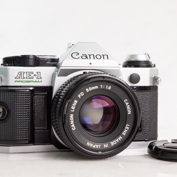 Canon AE-1 Program 35mm Film SLR Camera with Canon FD 50mm F/1.8 Standard Fast Prime Lens, Lens Cap, and Battery