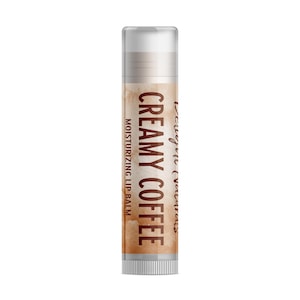 May include: A lip balm tube with a clear cap and a label featuring the words "CREAMY COFFEE" in brown. The label has a coffee-coloured background and the text "MOISTURISING LIP BALM". The tube is cylindrical.