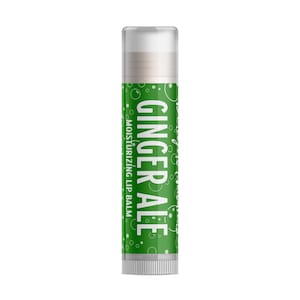 May include: A lip balm tube with a green label. The label displays "Ginger Ale" in white script and "Moisturizing Lip Balm" in smaller white text. The tube has a white cap and base. The product is designed to moisturize lips.