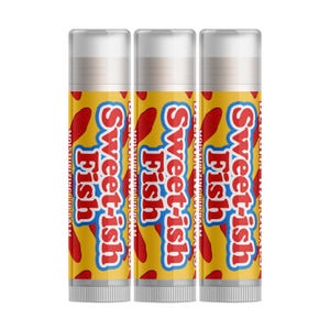 Puede incluir: Tres tubos de bálsamo labial con el texto "Sweetish Fish" en rojo y blanco sobre un fondo amarillo. Los tubos también tienen gráficos de peces rojos y las palabras "Moisturizing Lip Balm". Las tapas son blancas.