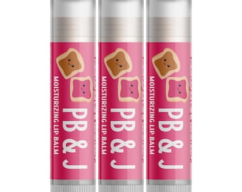 May include: Three lip balm tubes with a pink background. Each tube features a cartoon peanut butter and jelly sandwich illustration. The text "PB & J" and "Moisturizing Lip Balm" are printed on the tubes.
