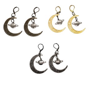 Op de afbeelding: Een paar halve maan oorbellen met een kleine planeet charme die aan elke oorbel hangt. De oorbellen zijn verkrijgbaar in drie afwerkingen: goud, zilver en brons.