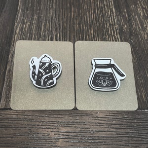 May include: Two black and white illustrations of coffee makers on a beige background. The first illustration is of a coffee pot with a spout and a handle. The second illustration is of a pour-over coffee maker.