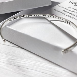 May include: A silver bangle bracelet with the inscription "☆ She believed she could, so she did..."