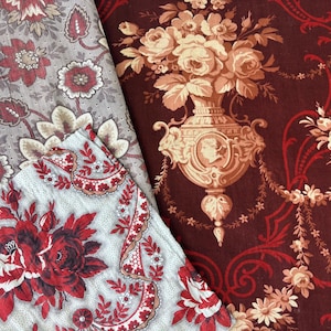 Puede incluir: Dos piezas de tela con motivos florales. Una pieza es de color rojo intenso con una urna de color tostado claro y motivos florales. La otra pieza es de color gris claro con un denso patrón de flores rojas y marrón oscuro, hojas y bordes decorativos.
