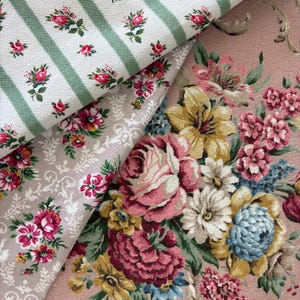 Pode incluir: Três camadas de tecido são exibidas. A camada superior apresenta listras verdes com pequenos botões de rosa cor-de-rosa. A camada intermediária é um tecido bege claro com padrão floral rosa. A camada inferior é um tecido rosa poeira.