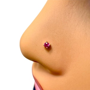 Peut inclure: Un gros plan d'un anneau de nez en pierre précieuse rose. L'anneau est en or et a une petite pierre ronde.