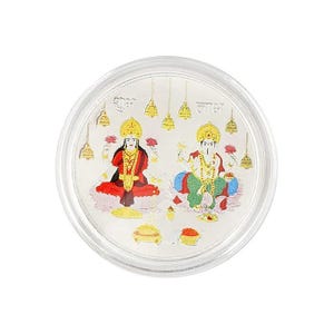 Puede incluir: Una moneda redonda de plata con ilustraciones coloridas de las deidades hindúes Lakshmi y Ganesha. La moneda tiene detalles dorados y texto en escritura. La moneda está encerrada en un marco circular transparente.