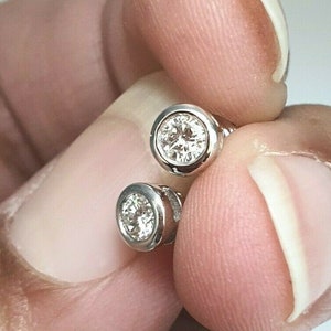 Op de afbeelding: Een paar zilveren oorbelletjes met ronde, heldere edelstenen.