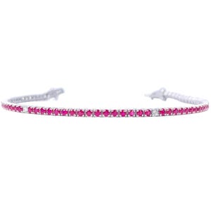 May include: A delicate silver bracelet set with numerous small, vibrant red gemstones. The bracelet has a slender design with a single, small white gemstone accent. The bracelet is set against a white background.