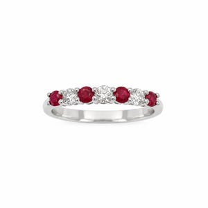 May include: A silver-toned band ring featuring a row of seven alternating round-cut gemstones. The design includes four deep red rubies and three clear white diamonds set in a prong setting, creating a symmetrical pattern across the top of the ring.