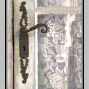 Könnte beinhalten: Eine Nahaufnahme eines Türgriffs im Vintage-Stil mit filigranen Details. Der Griff ist aus dunklem Metall und hat ein Schlüsselloch. Der Griff ist an einer weißen Holztür befestigt.