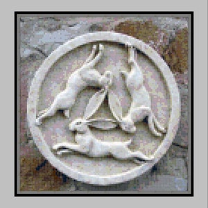 Puede incluir: Una escultura de piedra circular en relieve de tres liebres, cada una con la cabeza girada para mirar la cola de la liebre que está delante, creando un bucle continuo.