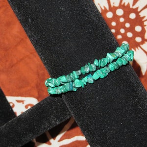 May include: A double strand bracelet made of green malachite chips. The bracelet is displayed on a black velvet jewelry stand.