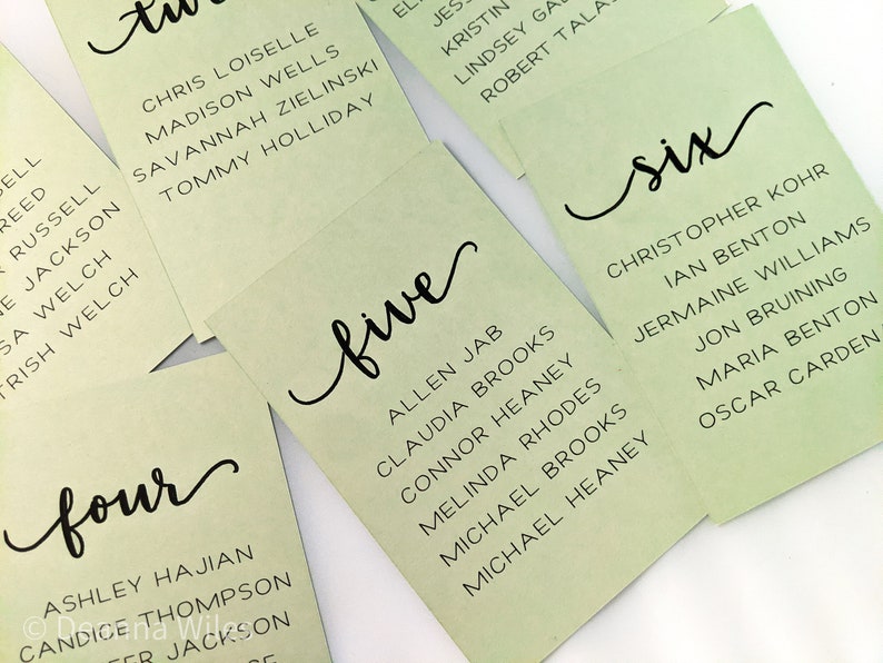 May include: Green table cards with black calligraphy numbers and names. The numbers are 'four', 'five', and 'six'.