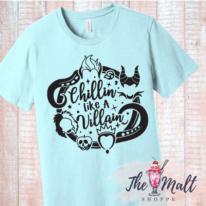 May include: Light blue t-shirt with a black graphic design featuring a circle with various Disney villain icons and the text "Chillin' like a Villain".