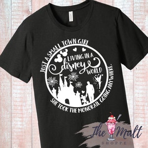 May include: Black t-shirt with a white circle graphic featuring a Disney castle, fireworks, Mickey Mouse ears, and the text "Just a small town girl living in a Disney world. She took the monorail going anywhere."