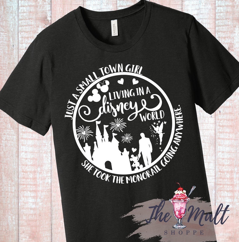 May include: Black t-shirt with a white circle graphic featuring a Disney castle, fireworks, Mickey Mouse ears, and the text "Just a small town girl living in a Disney world. She took the monorail going anywhere."