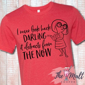 May include: Red t-shirt with a black graphic of a woman with glasses and the text "I never look back darling it distracts from the now".