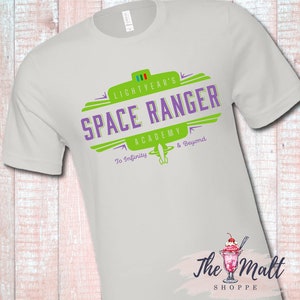 May include: White t-shirt with a green and purple logo that says "Lightyear's Space Ranger Academy To Infinity & Beyond".