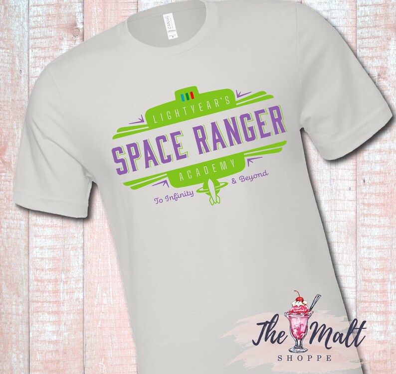 May include: White t-shirt with a green and purple logo that says "Lightyear's Space Ranger Academy To Infinity & Beyond".