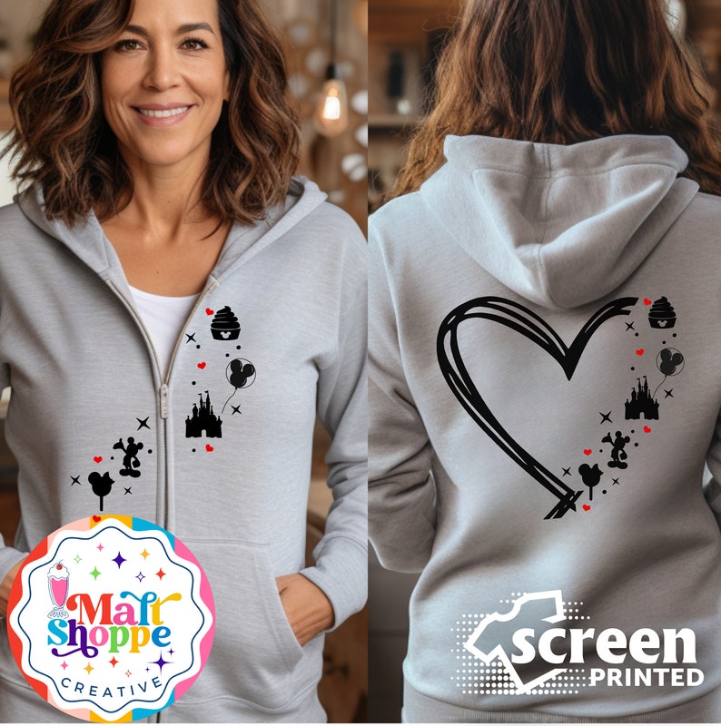 May include: A light gray zip-up hoodie featuring black and red graphic designs of a castle, Mickey Mouse, and a cupcake. The back of the hoodie has a large black heart design. The hoodie has a white zipper.