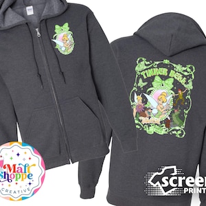 May include: A dark gray zippered hoodie with a green Tinker Bell graphic on the front and a larger green Tinker Bell graphic on the back. The back graphic includes the text "Tinker Bell" and "Never Grow Up".