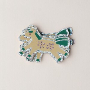 May include: A stack of glittery gold and green horse stickers. The horse has a green mane and tail and is decorated with pink flowers.