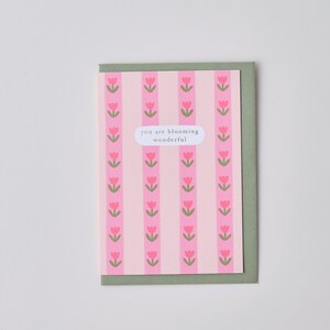 May include: A pink and green card with a repeating pattern of pink tulips. The card has the text "you are blooming wonderful" in a white circle.