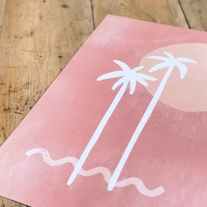 May include: A pink and white print with two palm trees and a large orange sun. The print has a wavy line at the bottom, representing the ocean.