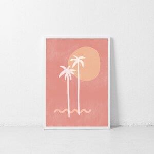 May include: A digital art print featuring two white palm trees with a large orange sun behind them on a pink background. The trees are stylized and the sun has a textured look. The print is framed in a white frame.