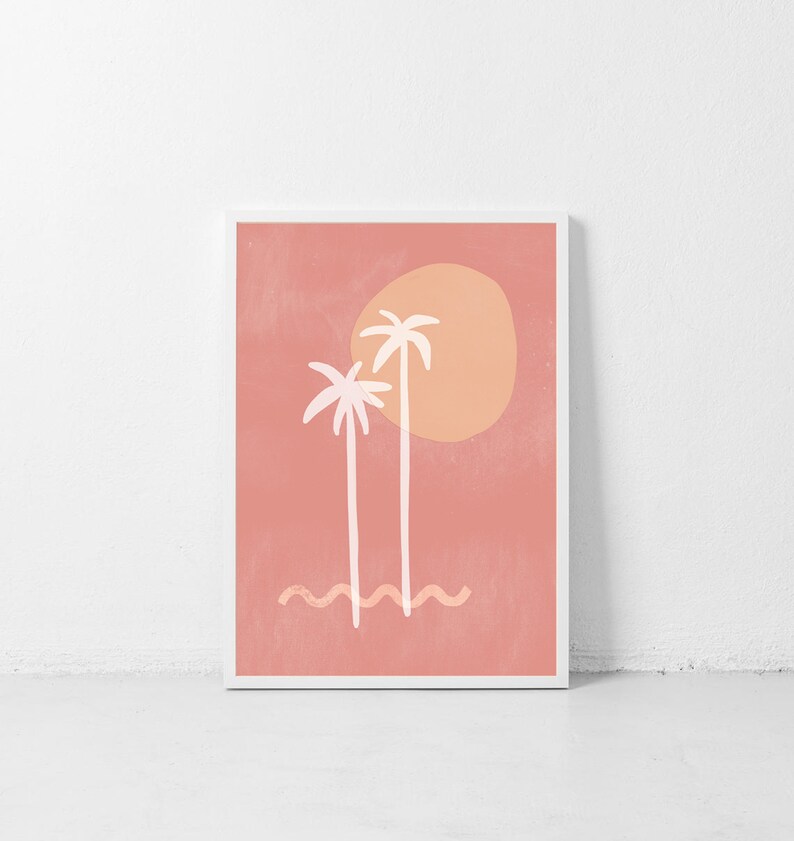 May include: A digital art print featuring two white palm trees with a large orange sun behind them on a pink background. The trees are stylized and the sun has a textured look. The print is framed in a white frame.