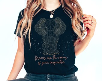 May include: Black t-shirt featuring a detailed gold elephant design with intricate patterns. The shirt includes the text "Dreams are the canvas of your imagination" in a cursive font. The design is set against a backdrop of small star-like elements.