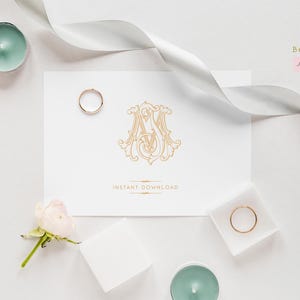 May include: A flat lay featuring a white card with a gold monogram and the words "INSTANT DOWNLOAD". Two gold rings, candles, flowers, and a white ribbon are arranged around the card. The image has a soft, romantic aesthetic.