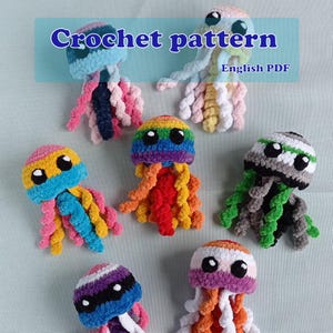 May include: A selection of crocheted jellyfish in various colours. Each jellyfish has a round head with large, black eyes and long, curly tentacles. The heads are in different colours, including rainbow, blue, pink, and green. The text "Crochet pattern" and "English PDF" are visible.