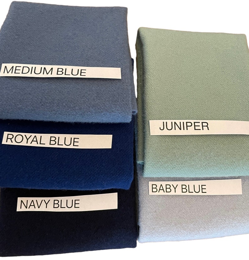 May include: A collection of fabric swatches in various shades of blue and green. The swatches are labeled with the following colors: Medium Blue, Royal Blue, Navy Blue, Juniper, and Baby Blue. The fabric appears to be a soft, textured material.