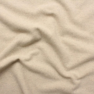 May include: Close-up of a beige fabric with a textured weave. The fabric is draped, creating soft folds and shadows. The color is a warm, neutral tone, suitable for various textile projects.