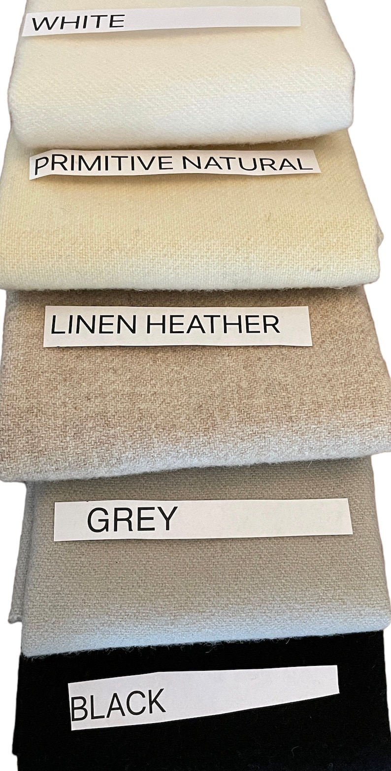 May include: A stack of fabric swatches in various colors: white, primitive natural, linen heather, grey, and black. Each swatch has a label with its color name. The fabrics appear to be woven.