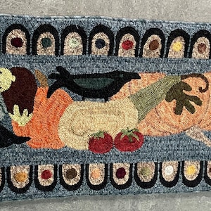 May include: A long, rectangular rug with a blue background and a colorful design. The design features a black crow, a pumpkin, a squash, a tomato, and a black dog. The rug has a black and white border with a repeating pattern of circles and arches.