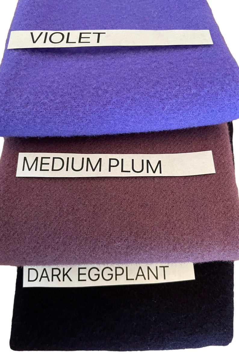 May include: A stack of fabric swatches in shades of purple. The top swatch is violet, followed by medium plum, and dark eggplant. Each swatch has a label with the color name in white text.