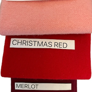 May include: Three fabric swatches in pink, Christmas red, and merlot. Each swatch has a label with the color name printed in black. The pink swatch is at the top, followed by the red and merlot swatches.