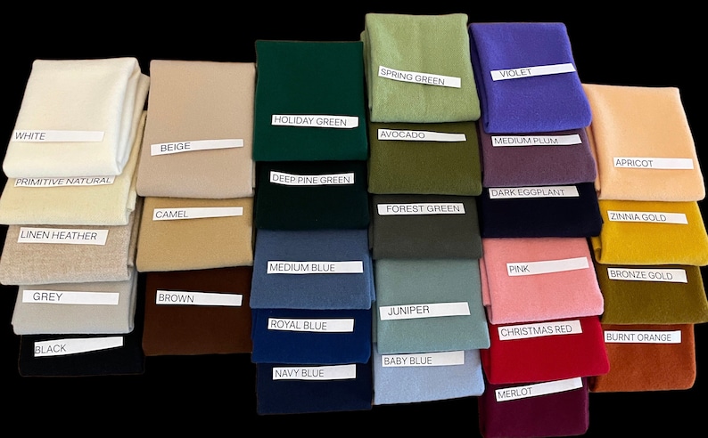 May include: A collection of folded fabric swatches in various colors, including white, beige, green, blue, and red. Each swatch has a label with its color name, such as "White," "Holiday Green," and "Merlot." The swatches are arranged on a black background.