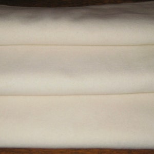 May include: Three white fabric squares stacked on top of each other. The fabric is smooth and has a slight sheen.