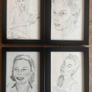May include: Four rectangular black frames containing graphite pencil portraits on white paper. Each frame displays a detailed sketch of a different individual, capturing facial features, hairstyles, and clothing in a realistic, monochromatic artistic style.