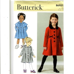 May include: A sewing pattern for a child's coat. The pattern includes three different styles: a blue coat with a cape, a plaid coat, and a red coat with a black collar and bow.